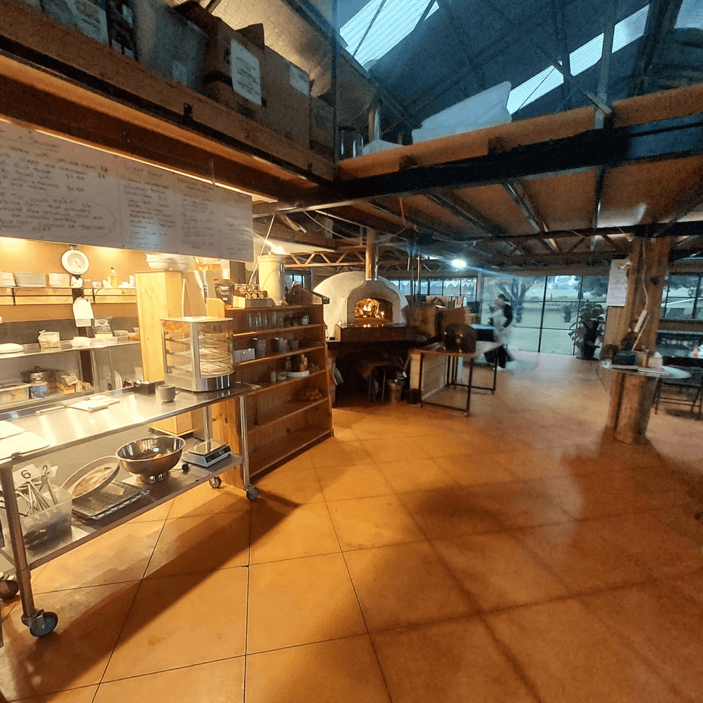 Modern farm café interior with wooden counters, display case, and warm lighting